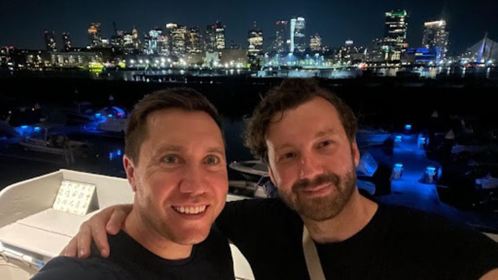 two men posed for a selfie in front of a skyline