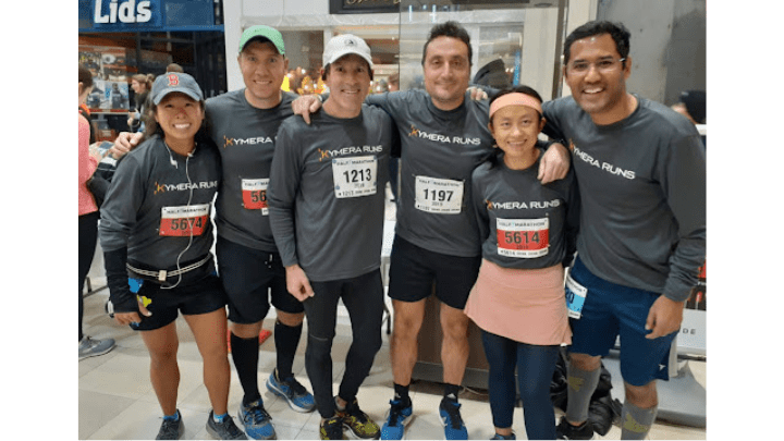 group of runners in matching kymera shirts with race bibs