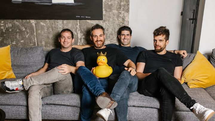 Four men sitting on couch with large rubber duck