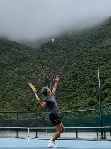 man serving a tennis ball in the fog