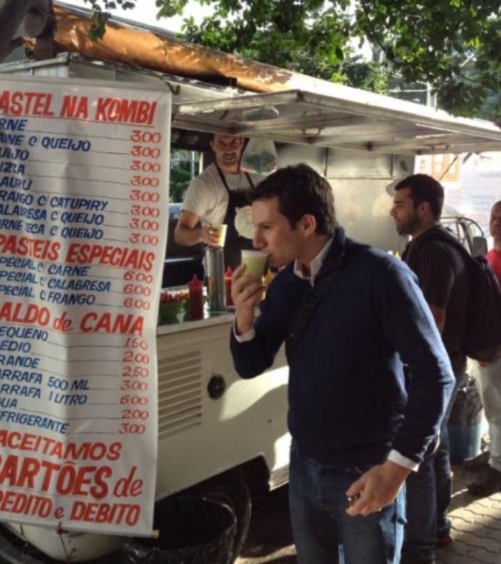 man drinking something in front of food truck