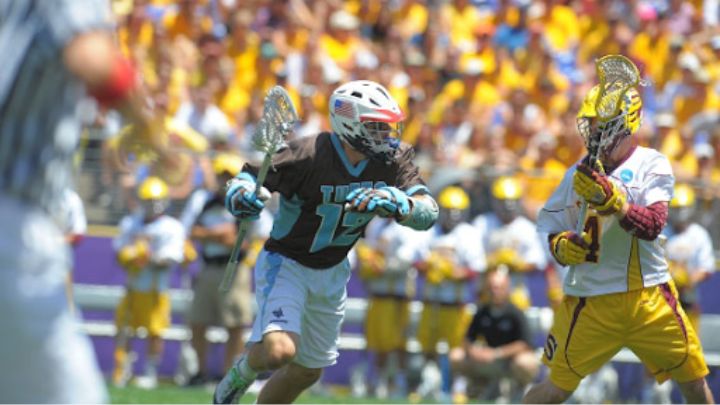 man playing lacrosse in front of crowd