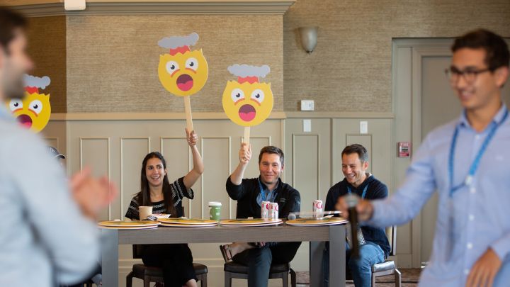 judges seated behind table holding up exploding mind emojis